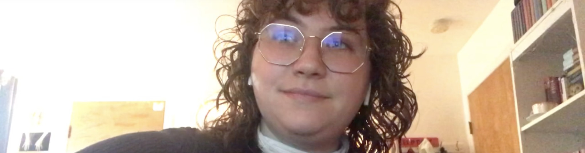 A portrait of a person wearing glasses and with curly hair.