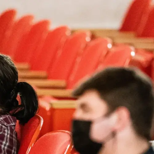 Students sit distanced and masked in an auditorium classroom