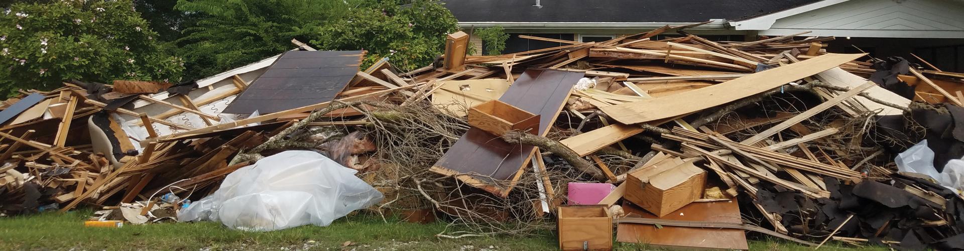 A big pile of wood scraps, nearly coming up to the top of the house in the background.