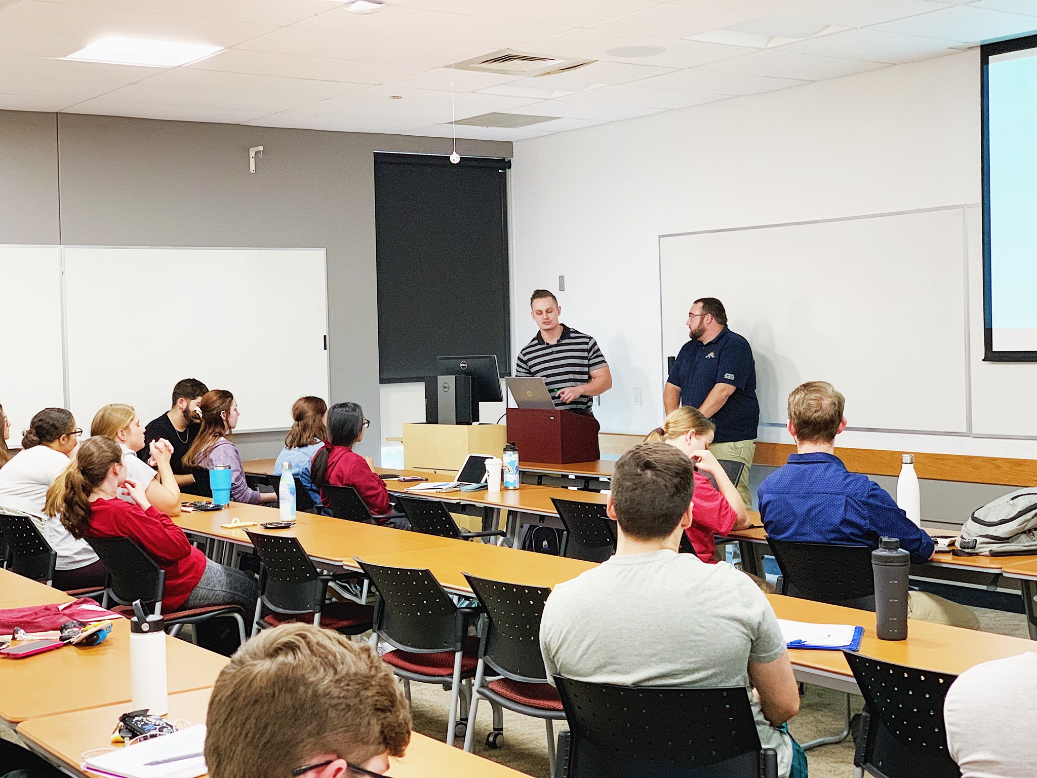 Two professor giving a lecture in a classroom full of students