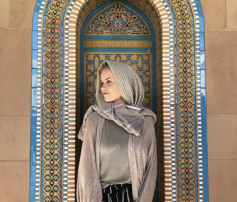 An Arcadia student poses in front of religious tiles overseas.