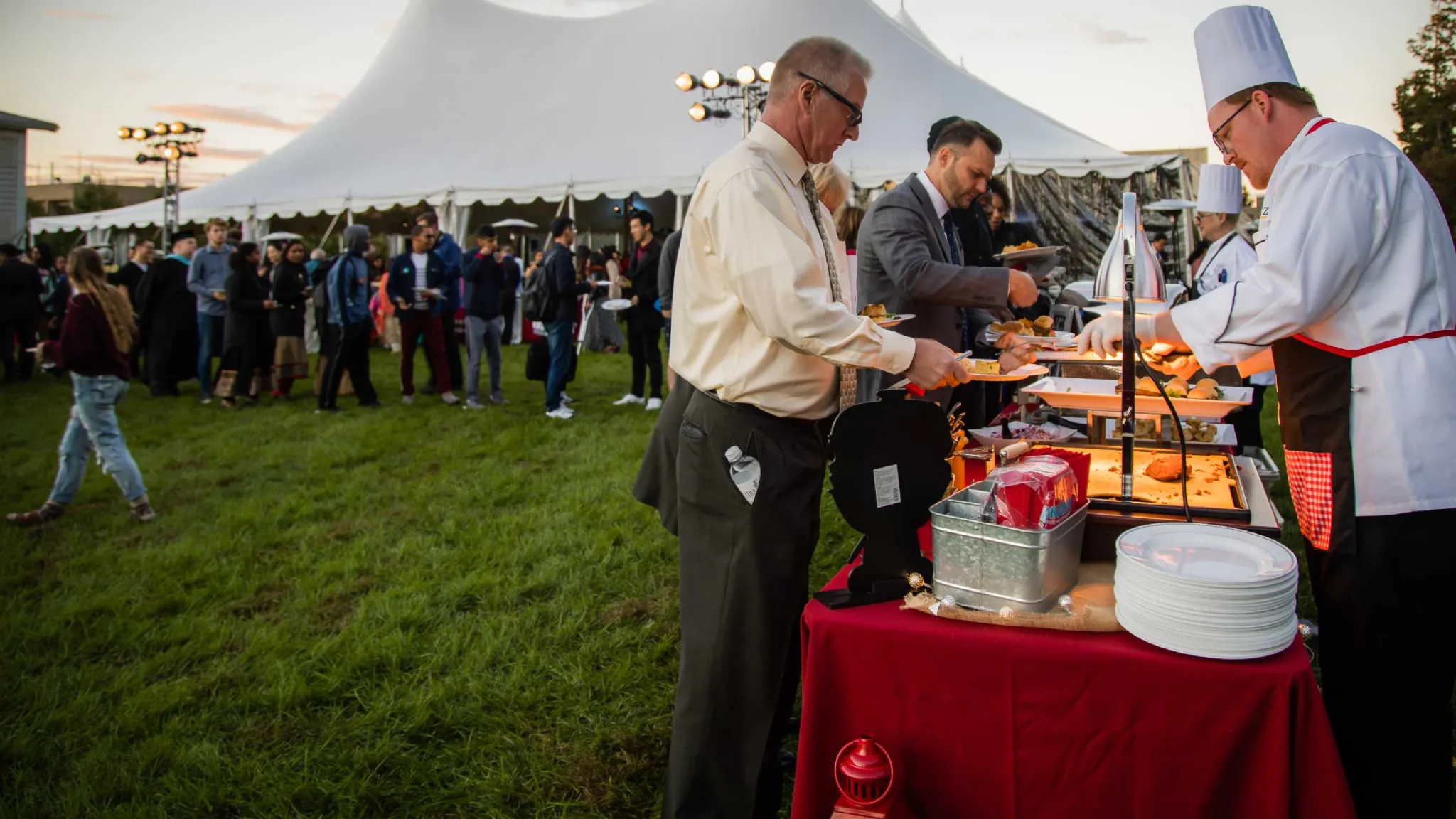 Outdoor catered event with chef and many guests