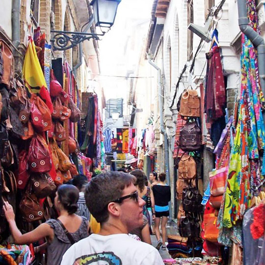 A student walks through a lively street in Granada, Spain.