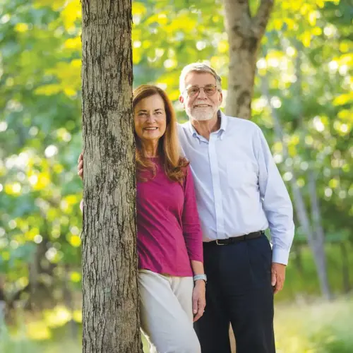 Alumni Weber family smiling at the camera while posing against a tree.