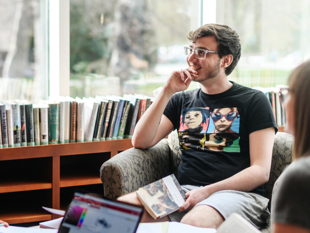 Students meet at the library with their laptops and books open.