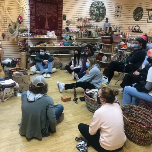 A group of people sitting together in a room full of pottery-like objects