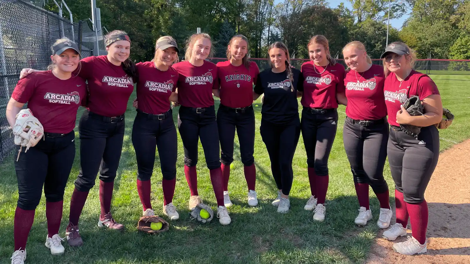 Members of the softball team stand in a line.