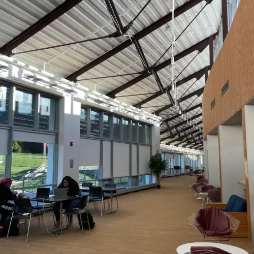 The second floor of University Comms, where two students sit facing each other at a table doing work on their laptops