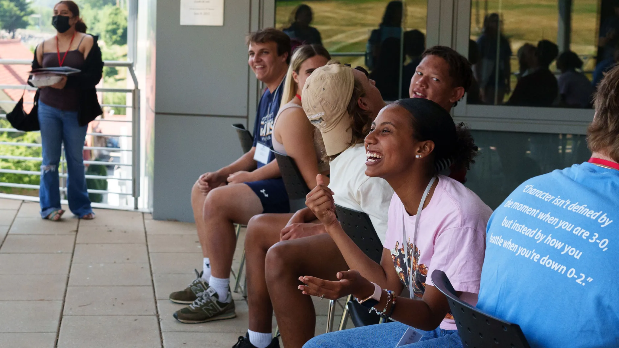 Students laughing and sitting in chairs outside during orientation