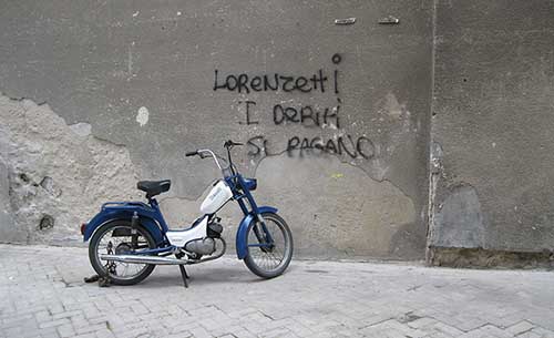 a photo of a motorbike in front of a concrete wall with graffiti