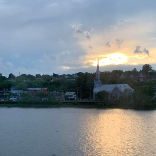 The sunset with a body of water in the foreground and a city in the background