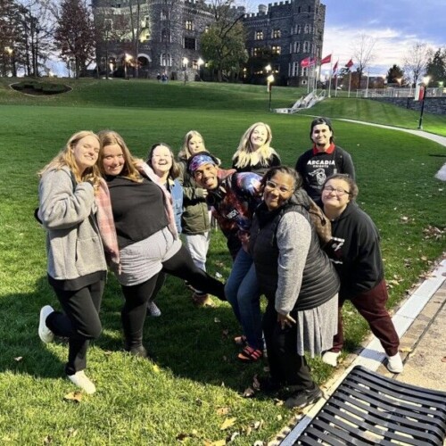 A group of students poses for a photo on Haber Green at dusk