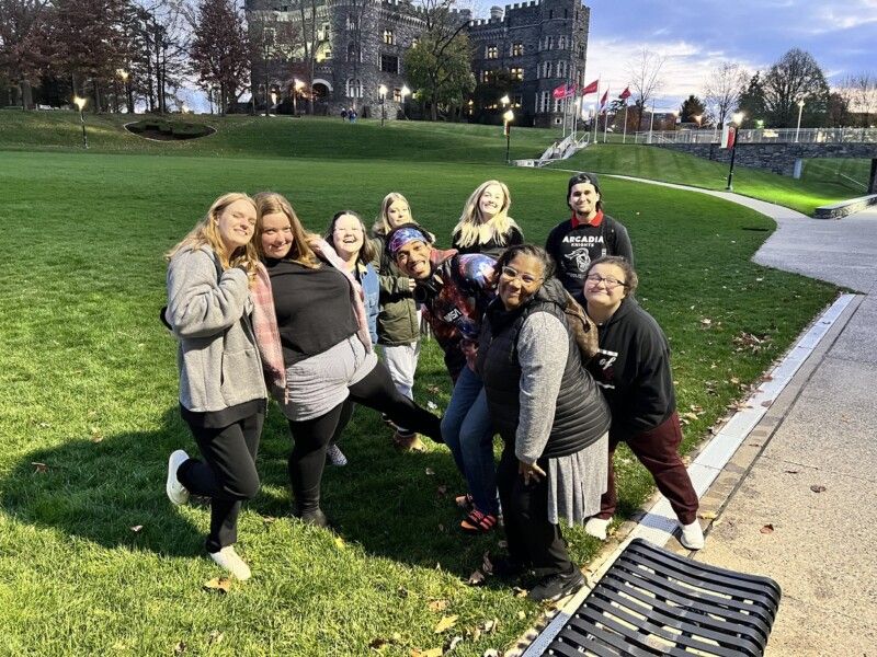 A group of students poses for a photo on Haber Green at dusk