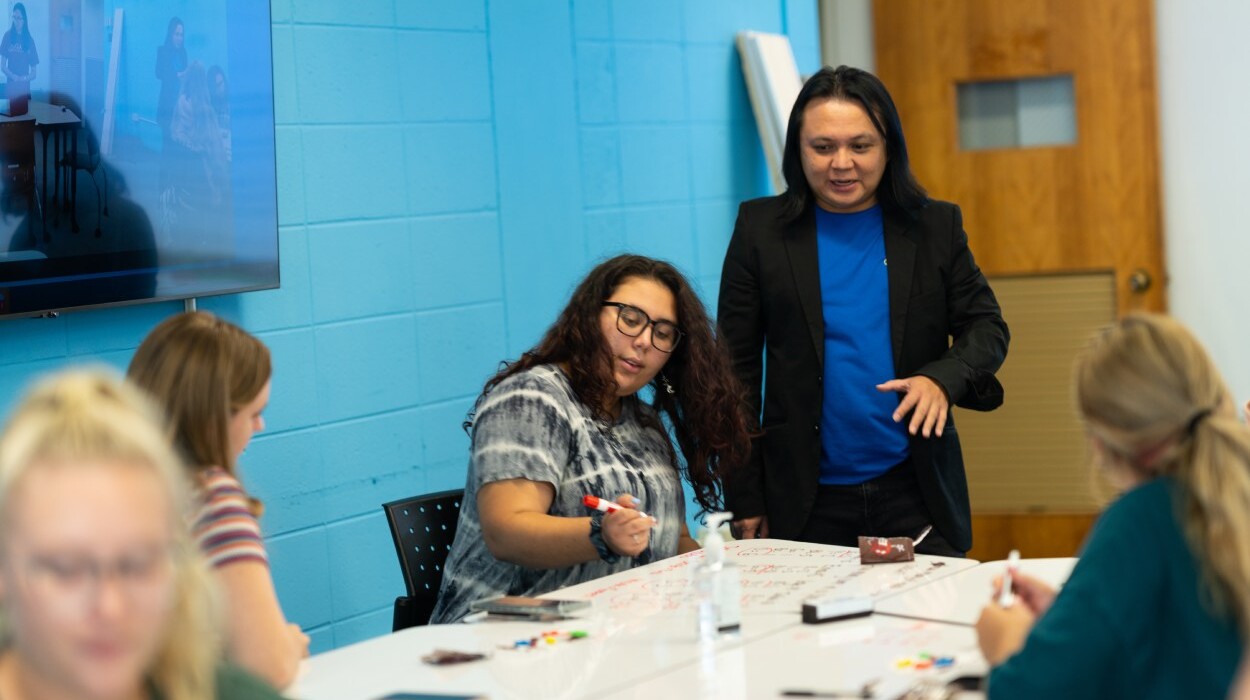 Students studying and interacting with their professor in a classroom