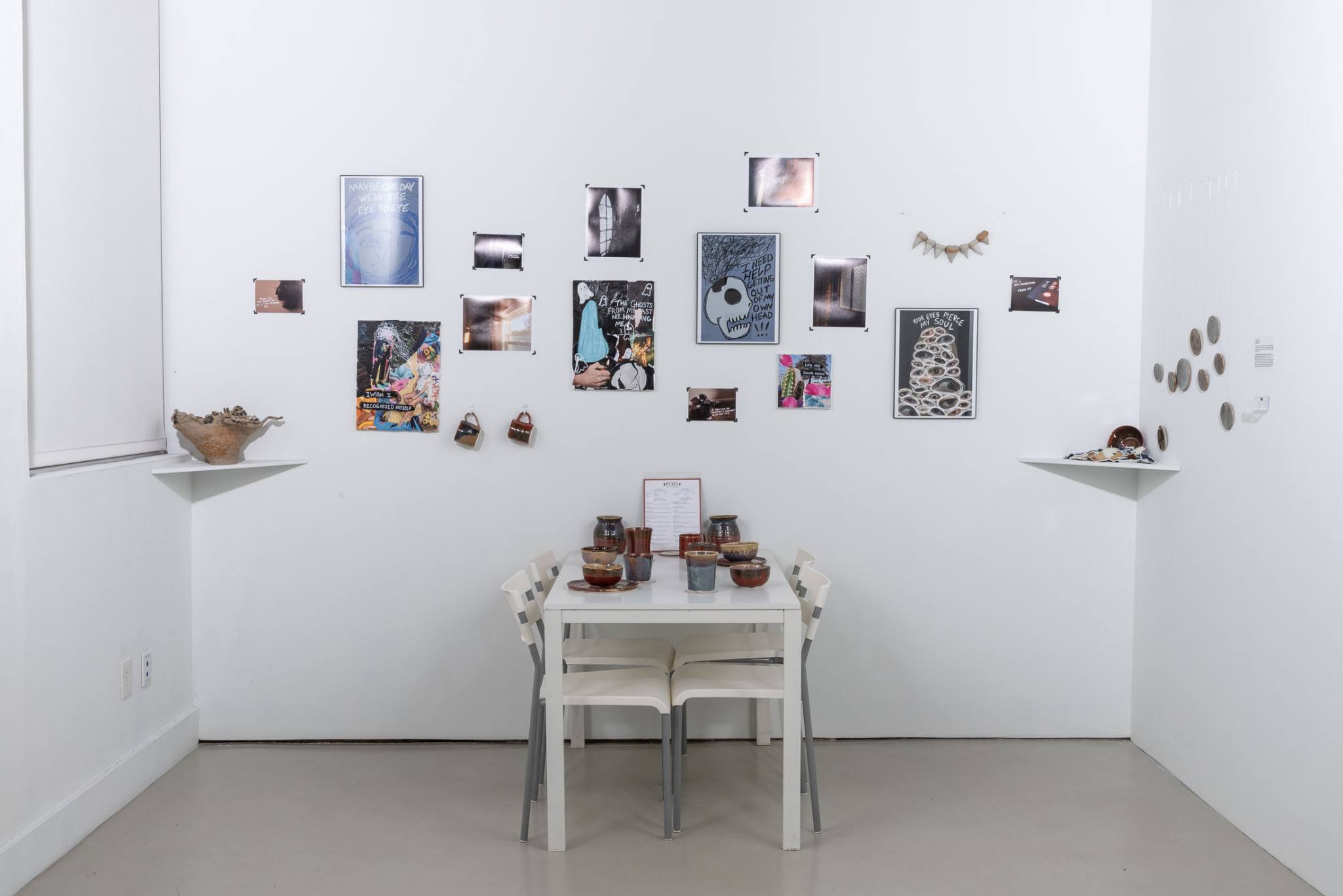 Several pieces of artwork on display on a white wall and table