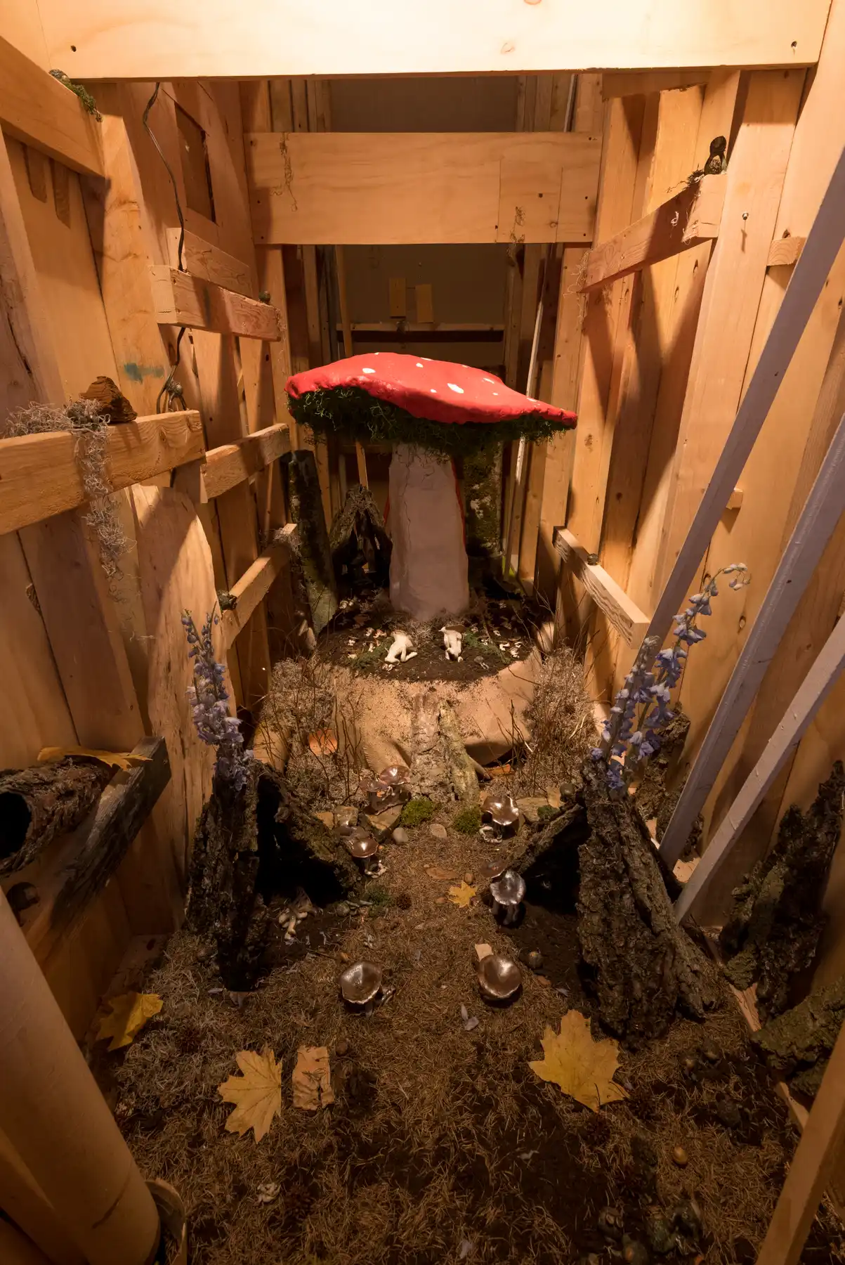 Large mushroom sculpture with wooden fences on the side and dirt on the ground