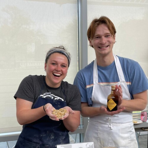 Two students hold the ingredients for a pasta dish at the Italy table at Global Expo