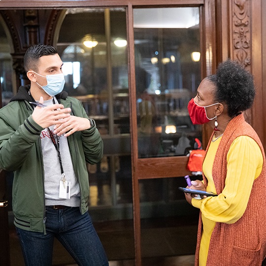 Two people talk in front of a doorway during a diversity and inclusion event.