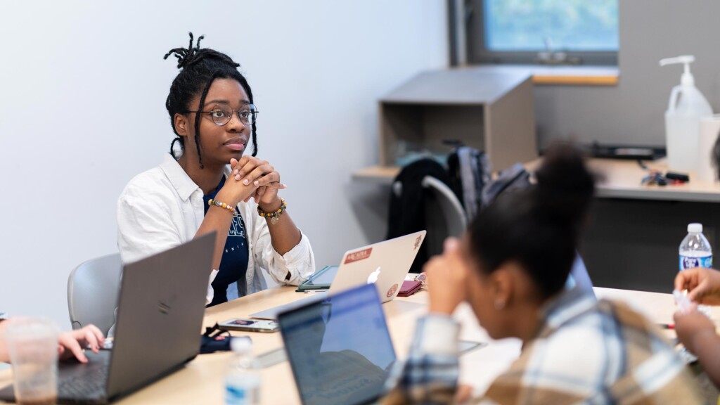 An Arcadia undergraduate student focuses on a classroom lecture as she folds her hands over a laptop computer.