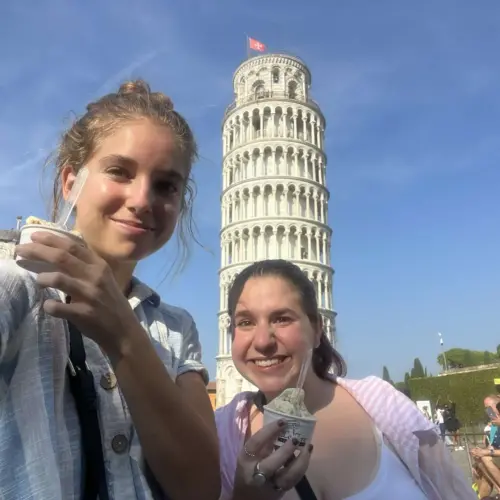 Sophie and her friend having ice cream with the leaning tower of Pisa behind them.