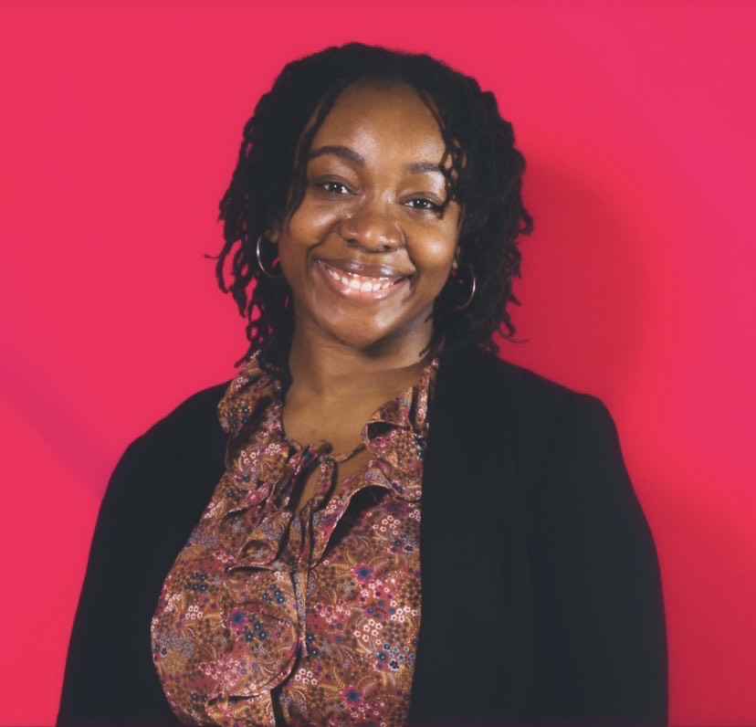 The headshot of a Black woman in a blouse with a black cardigan