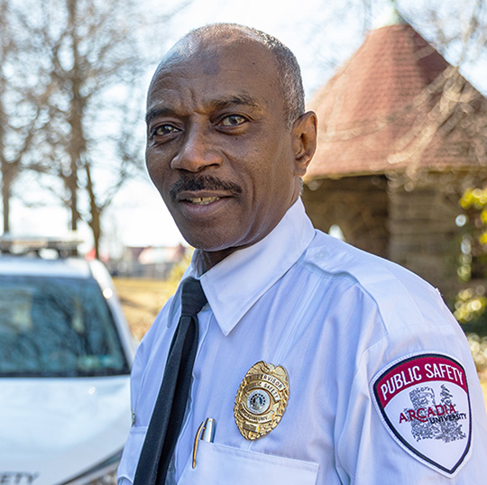 Sgt. Bruce Gant by a Public Safety vehicle on campus.