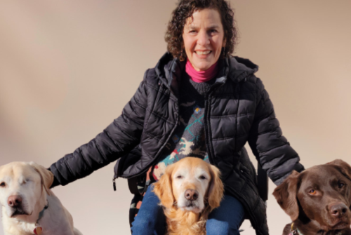 Alumna smiling with her three rescue dogs around her.