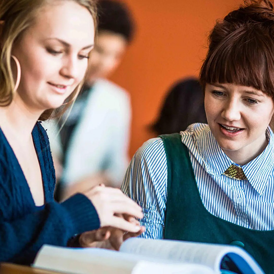 Two students study a text book during class at the School of Global Business.