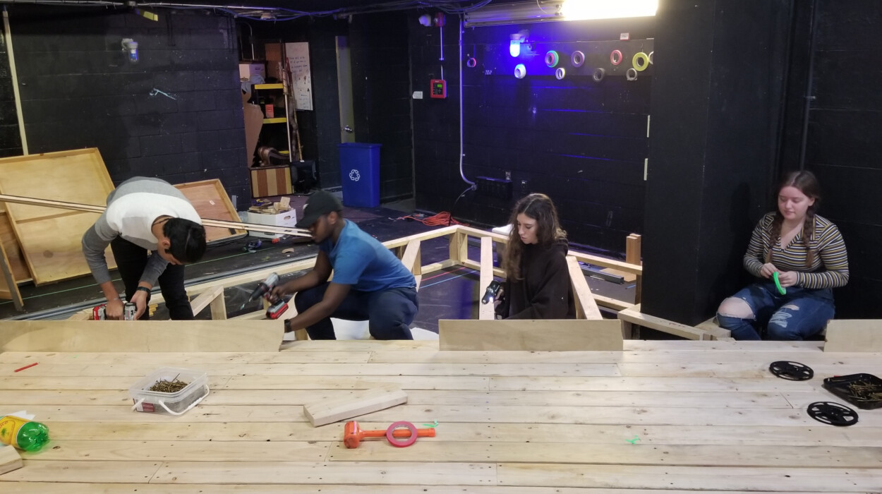 Four people working together to create a wooden platform