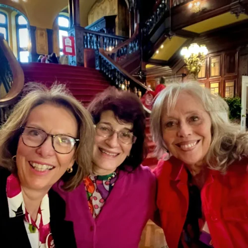 three alumnae standing together for a selfie picture in front of the stairs in the Grey Towers Castle