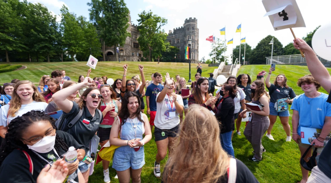 students on Haber Green standing in a circle and cheering with signs