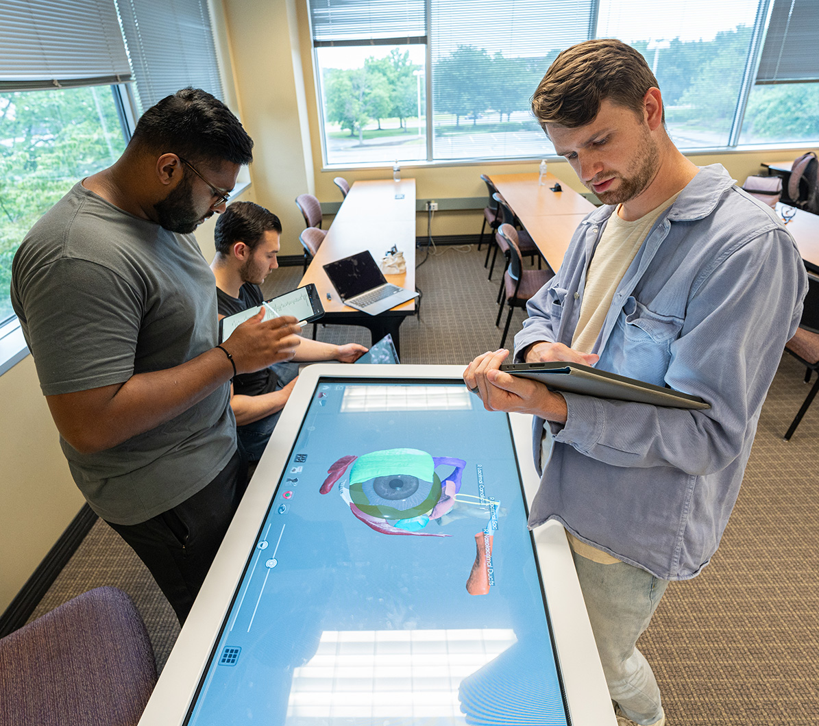 Two PA students work on a medical project ove a light table.