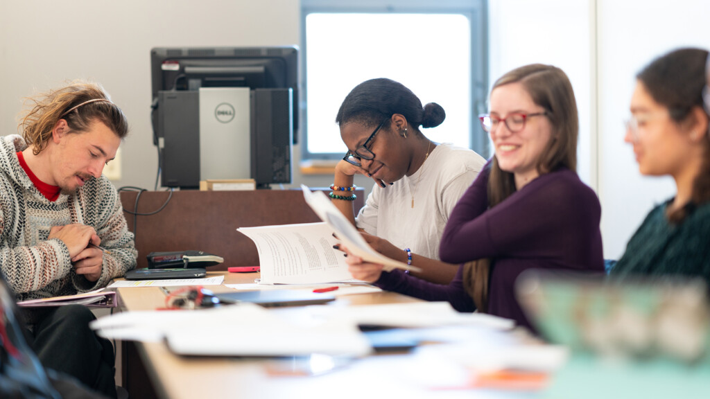 Students work on a project while sitting at a table in a classroom.