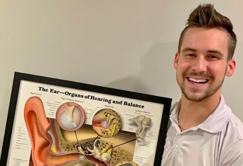 Kyle Kammerle holding a illustration of The Ear-Organs of Hearing and Balance