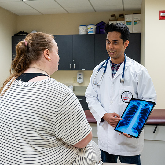 A Physician Assistant students shows an x-ray to a patient in a clinical setting.