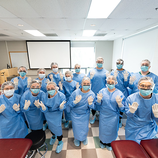 PA students stand in a clinical setting with scrubs on.