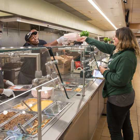 A customer and a food service worker at dining services.