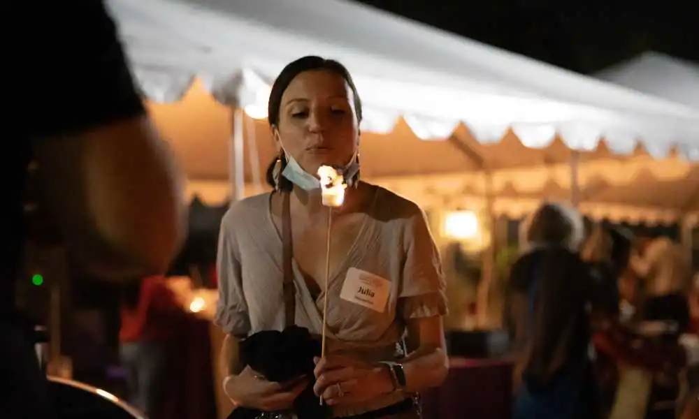 A student blows on a burning marshmallow at Homecoming events