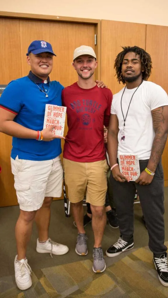 Three students stand together while smiling at the camera.