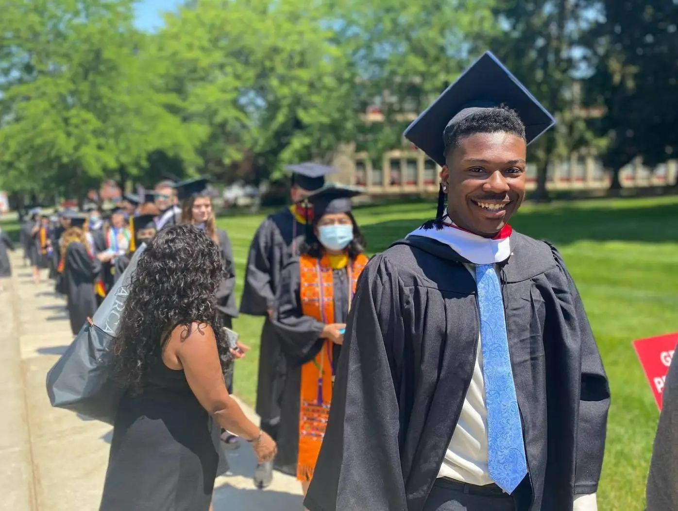 Arcadia's graduating students walk outdoors in caps and gowns and smile