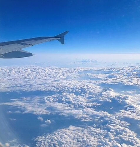 a photo from a plane window showing clouds and the wing of a plane