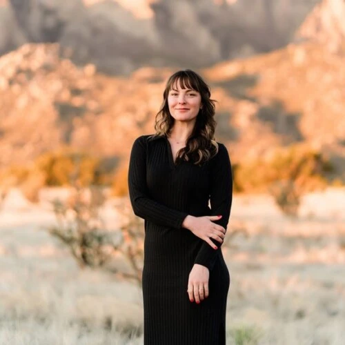 brown-haired girl standing in black dress amidst the New Mexico mountains and desert