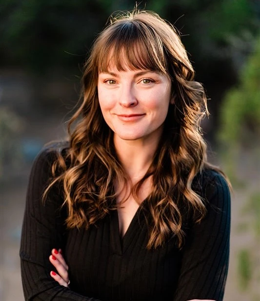 headshot of young brunette with a bright smile, no teeth showing