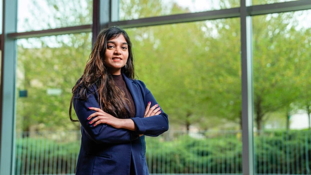 A woman in a professional attire, a blue suit, with greenery landscape behind