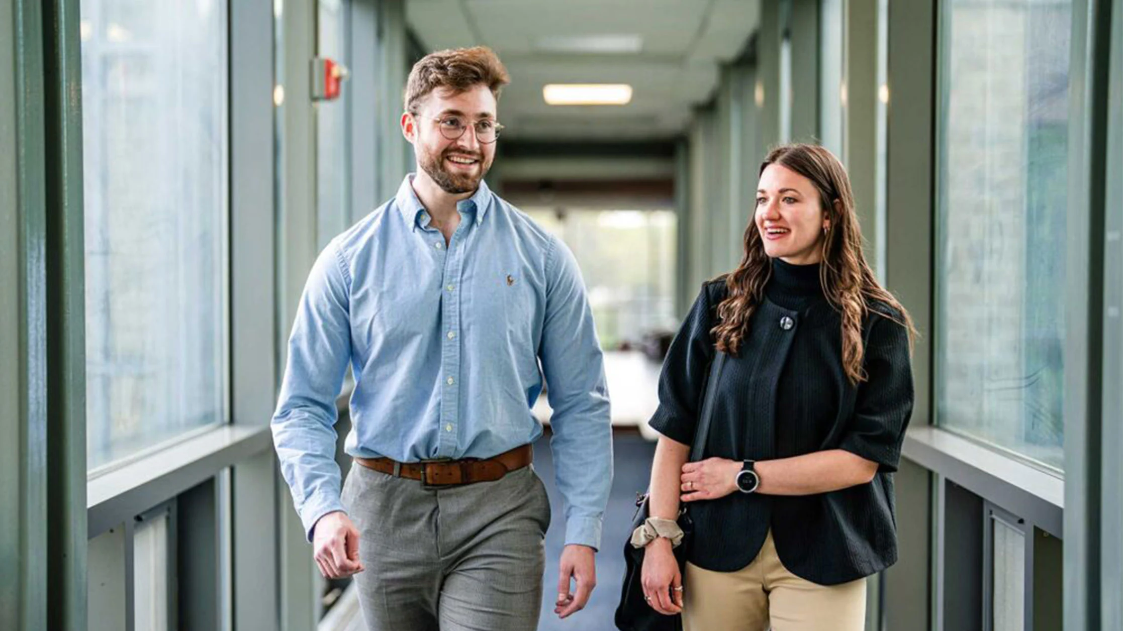 Two healthcare management students walking together in hall between buildings