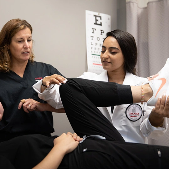 Erin Wolf works with a physician assistant student in a clinical practice setting.