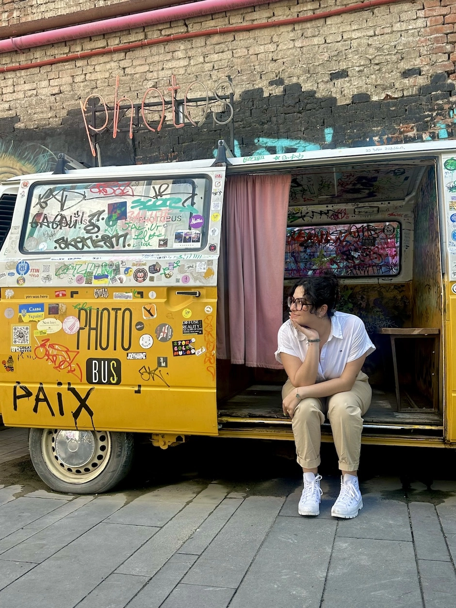 A woman sits in the open door of a van that says "Photo Bus" on the side