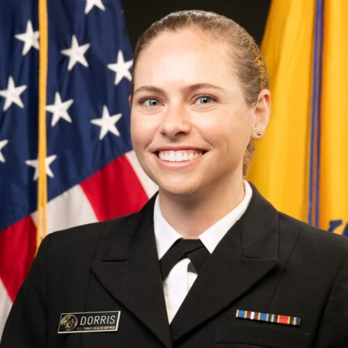 blonde woman smiling in government regalia in front of the USA flag